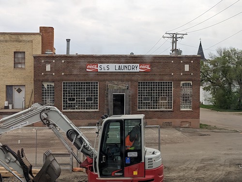 Exterior of S and S Laundry, an old abandoned building with a digger in front of it