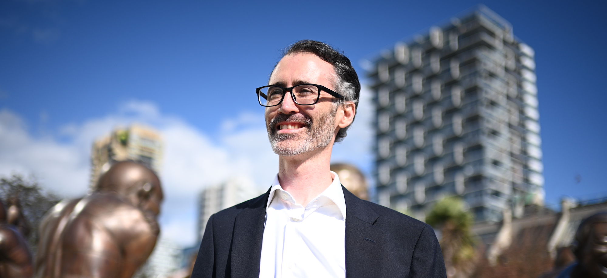 Eoin O'Dwyer in Vancouver's West End with the laughing statues behind him.